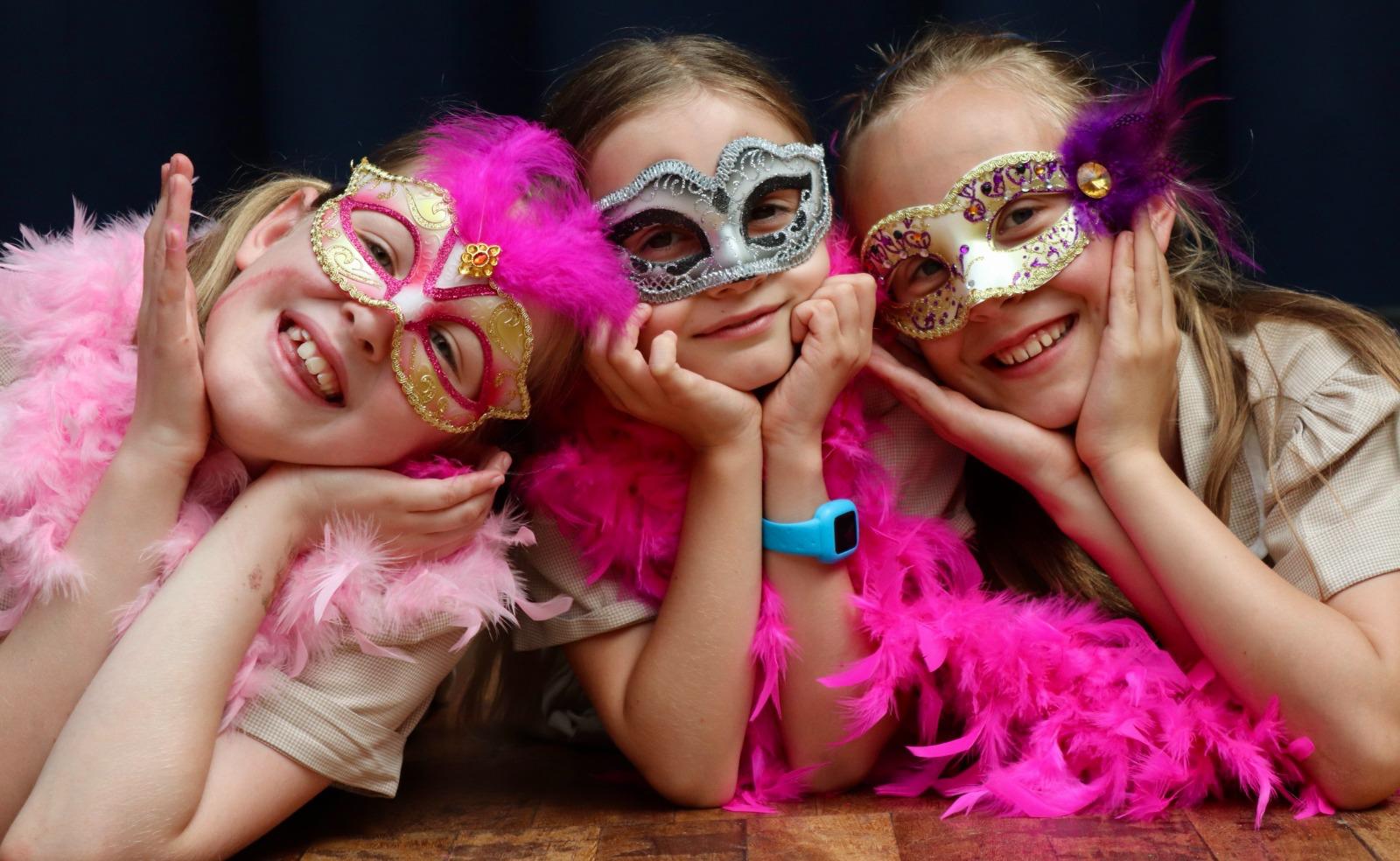 Three friends in masquerade masks smiling