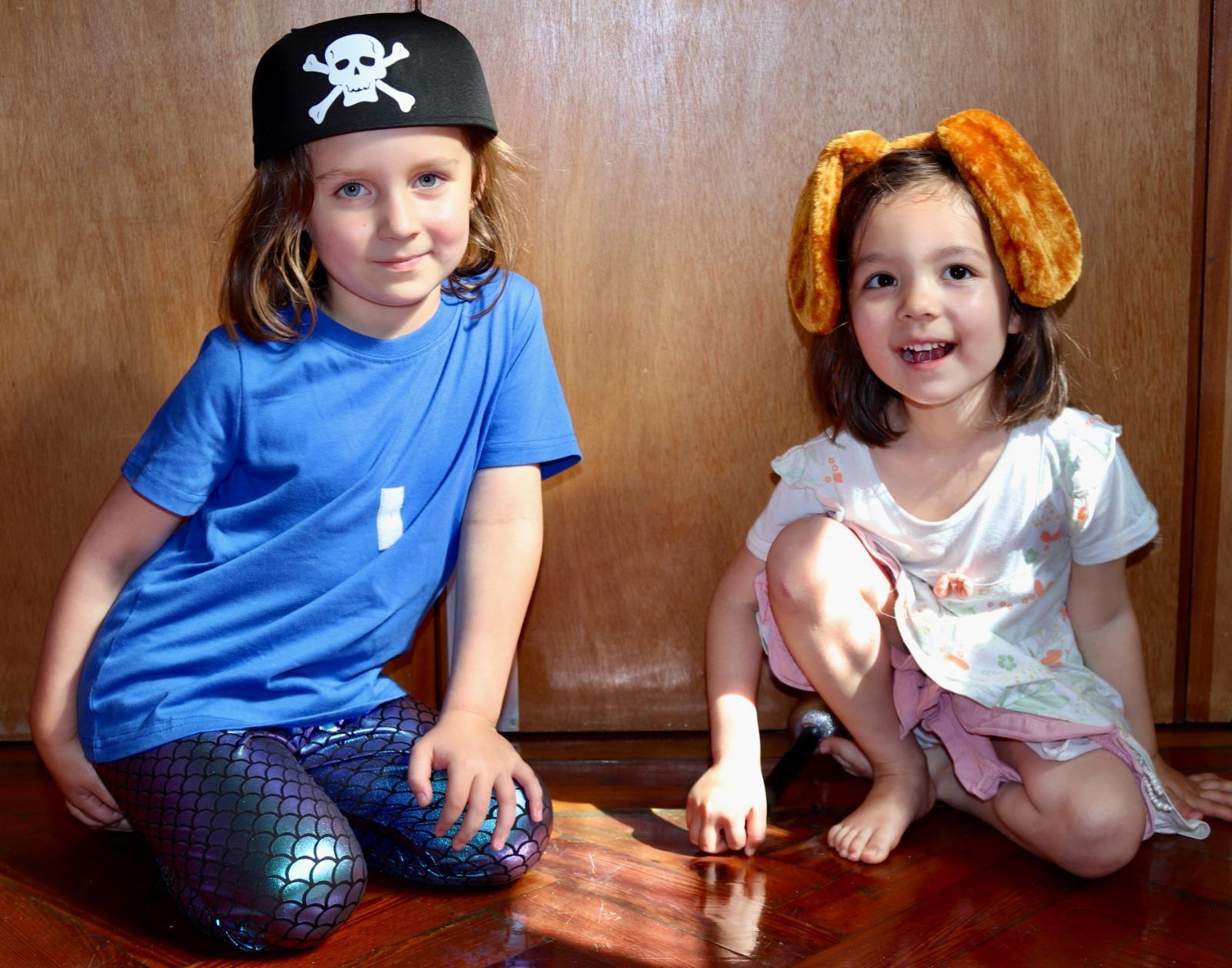 Two children dressed as a pirate and a puppy playing at home